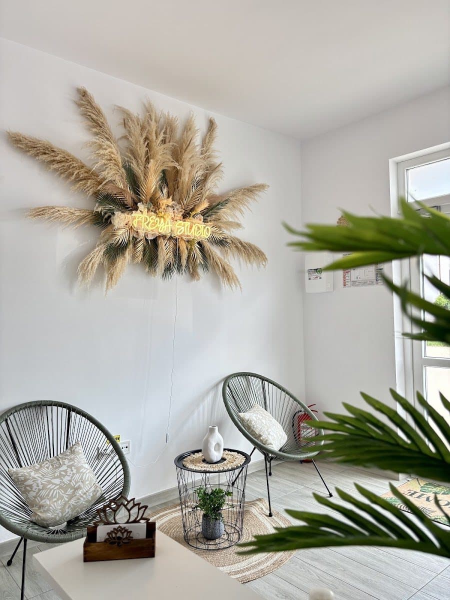 Semnul neon FREYA STUDIO pe perete cu iarbă pampas uscată